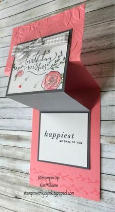 a pink and gray card with the words happy birthday written on it, sitting in front of a wooden background