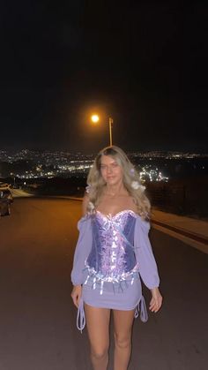 a woman in a corset standing on the side of a road at night