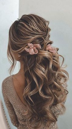 a woman with long curly hair and flowers in her hair is looking at herself in the mirror