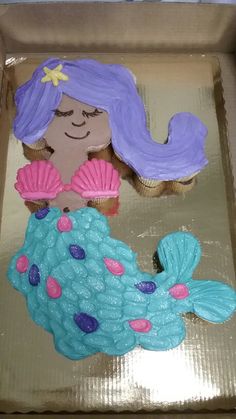 there is a cake shaped like a mermaid with blue hair and pink undershirt