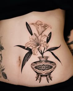 a woman's stomach with flowers in a vase tattoo on her side ribcage