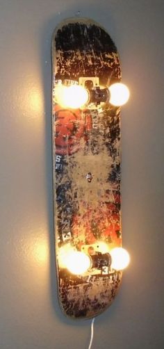 a skateboard with lights attached to the side of it hanging on a white wall