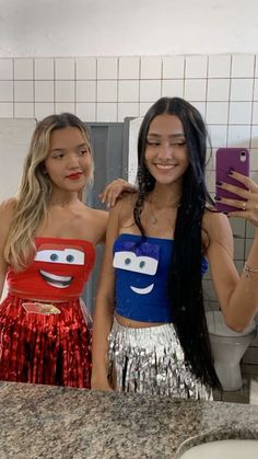 two young women standing next to each other in front of a bathroom mirror wearing costumes