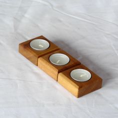 three tealight candles in wooden holder on white background