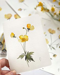 a person holding up a piece of paper with yellow flowers on it