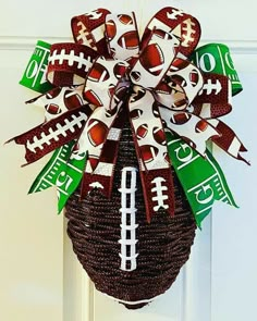 a football wreath hanging on the front door with green and white ribbon tied around it