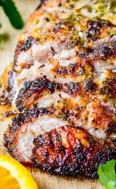 sliced pork on a cutting board with lemons and parsley