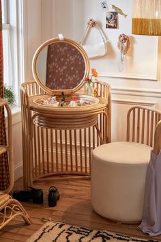 a round mirror sitting on top of a wooden table next to a white ottoman and chair