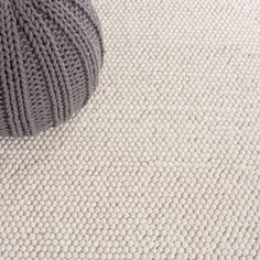 a ball of yarn sitting on the floor next to a gray and white carpeting