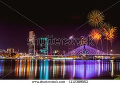 fireworks are lit up in the night sky over a river and cityscape with skyscrapers