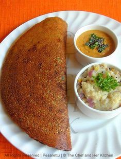 a white plate topped with food next to bowls of soup and bread on top of an orange table