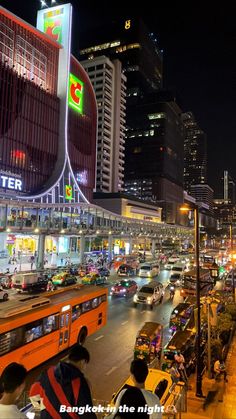 a city street filled with lots of traffic and tall buildings in the background at night