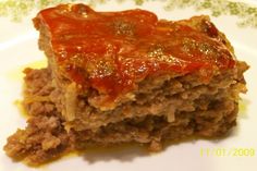 a piece of meatloaf on a plate with mashed potatoes and garnish