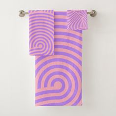 two purple and pink towels hanging on a towel rack in front of a white wall