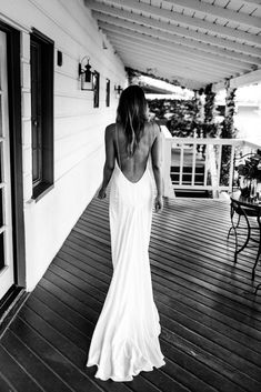 a woman in a white dress walking down a porch