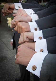 several people in suits and ties are holding their hands together with buttons on the lapels