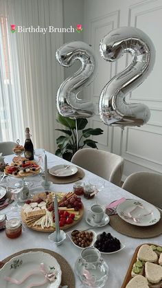 the table is set for two with balloons in the shape of numbers and desserts