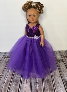 the doll is wearing a purple dress with sequins on it's waist