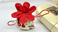 a red flower sitting on top of a white bag next to a sewing machine