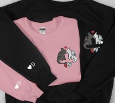 three sweatshirts with different designs on them, one is pink and the other is black