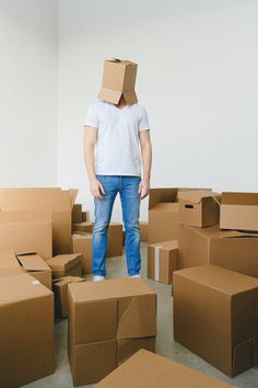 a man with a cardboard box on his head standing in a room full of boxes