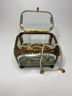 an antique jewelry box with pearls and glass in it's lid, sitting on a white surface