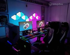 two computer monitors sitting next to each other in front of a purple and blue wall