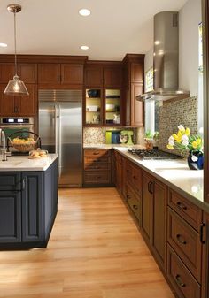 a large kitchen with wooden floors and stainless steel appliances, along with dark wood cabinets