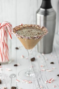 a drink in a martini glass with sprinkles and candy canes around it