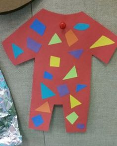 a paper cut out of a baby's body with geometric shapes on it next to a piece of tin foil