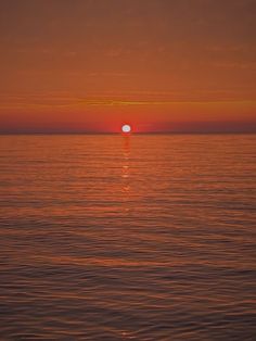 the sun is setting over the ocean as seen from a boat on the water,