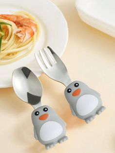 two plastic forks and spoons with cartoon penguins sitting on top of them next to pasta