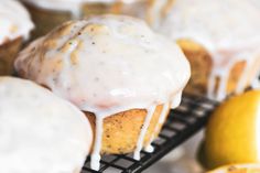 lemon muffins with icing on a cooling rack next to some lemons