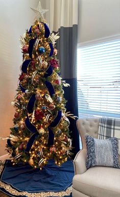 a decorated christmas tree in a living room with blue and gold decorations on the top