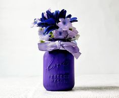 a purple mason jar filled with blue and white flowers