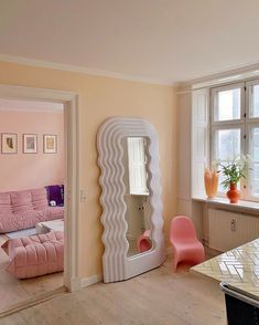 a living room filled with furniture and a large mirror on top of a wall next to a window