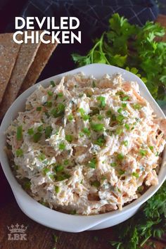 a white bowl filled with chicken salad and garnished with parsley on the side