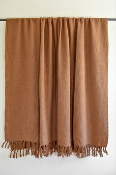 a brown blanket hanging on a wall with two tasseled ends and fringes