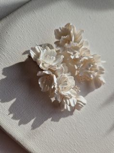 three white flowers sitting on top of a piece of cloth next to a window sill