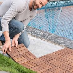 a man kneeling down next to a swimming pool with bricks on the ground in front of him