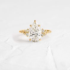 a pear shaped diamond engagement ring with yellow gold accents