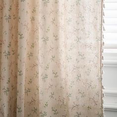 the curtain is hanging in front of a window with white curtains and flowers on it