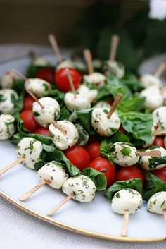 a white plate topped with tomatoes and mozzarella skewers