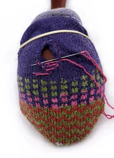 a purple and green knitted bag with a wooden handle