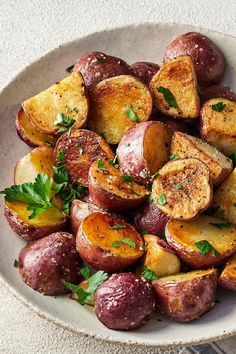 a white bowl filled with potatoes and parsley