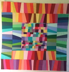 an art piece made out of different colored strips and squares on a wall with a white background