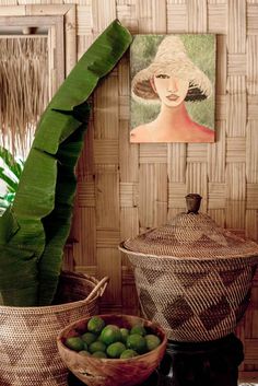 two baskets with fruit in them on a table next to a painting and a potted plant