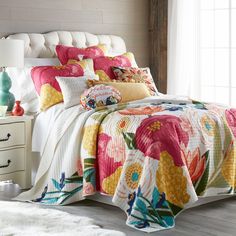 a bedroom with a bed covered in colorful quilts and pillows on top of it