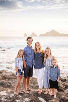 a family standing on rocks near the ocean