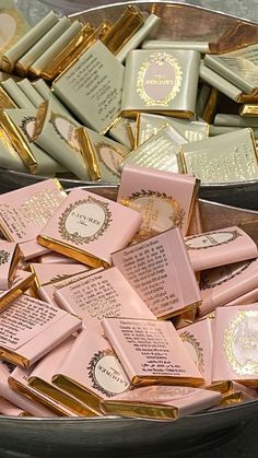 a bowl filled with lots of pink and gold candy bar wrappers on top of a table